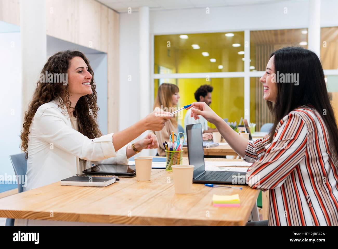 Donna d'affari che consegna la penna a un collega in ufficio Foto Stock