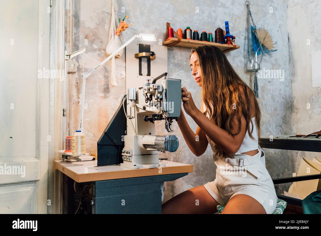 Stilista con macchina da cucire in officina Foto Stock