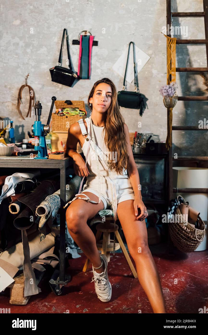 Giovane stilista seduto al banco di lavoro Foto Stock