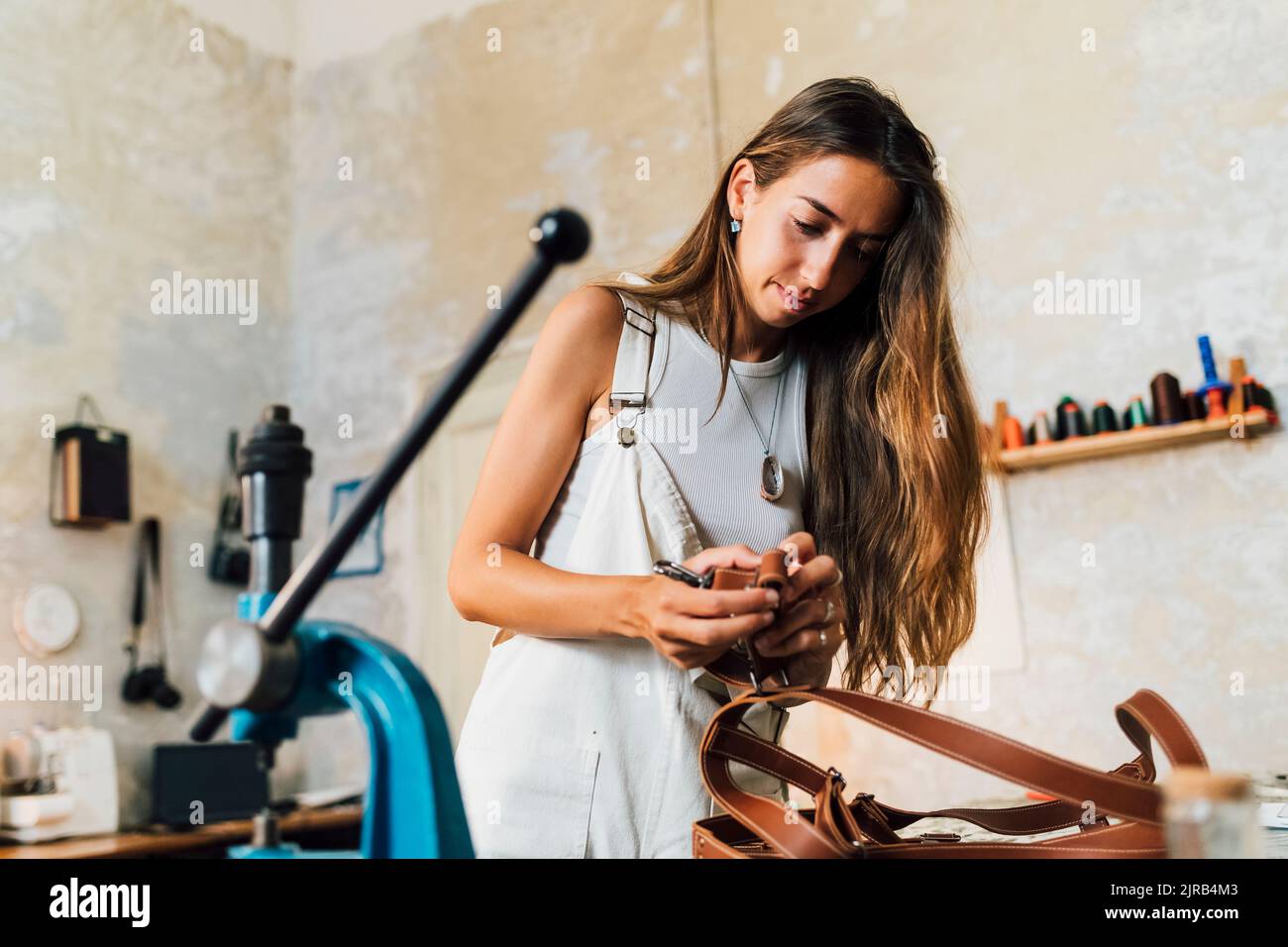Stilista di moda che fa accessori in pelle in officina Foto Stock