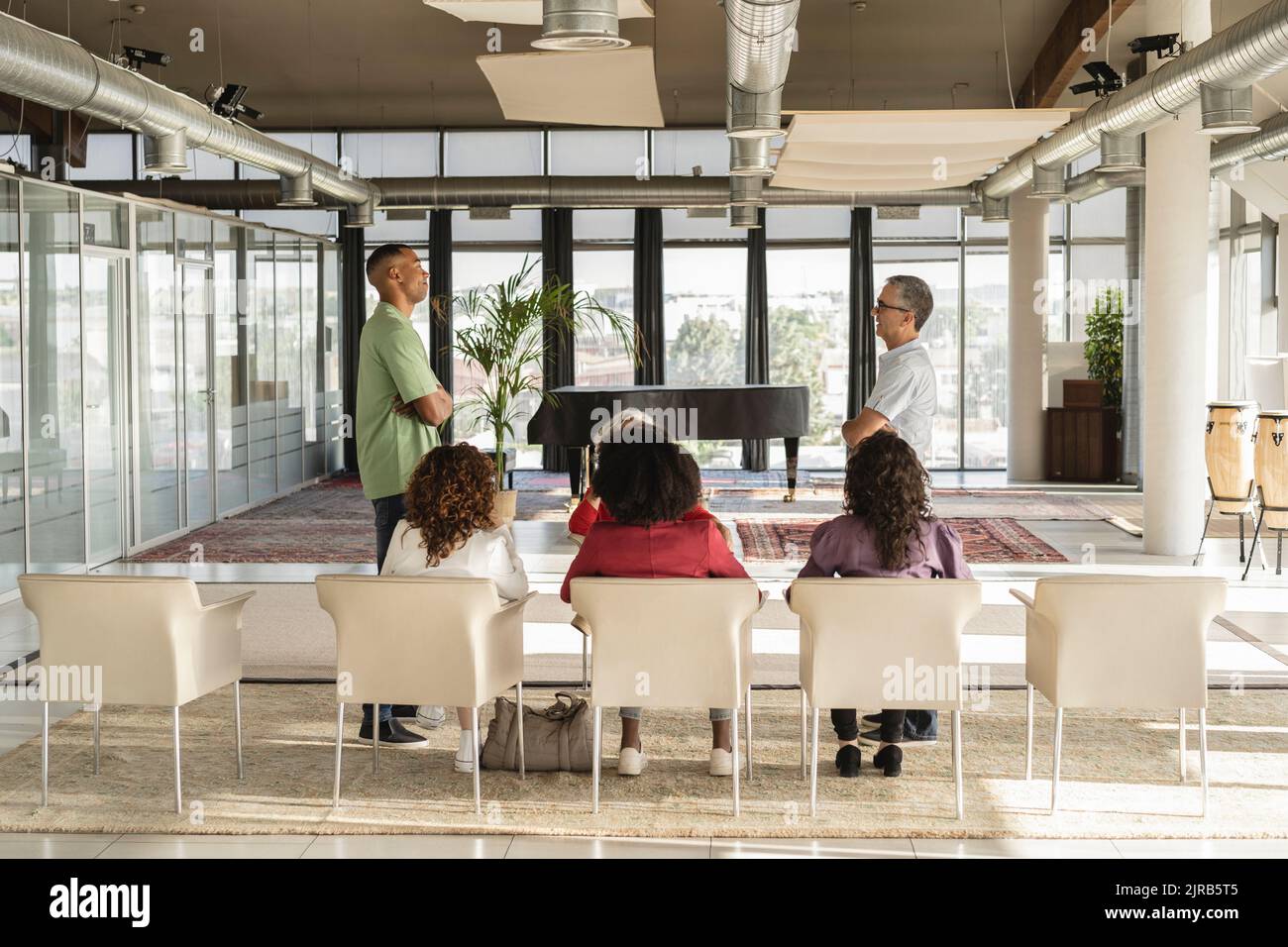 Uomini d'affari in piedi con le braccia incrociate condividere idee in sessione di brainstorming in ufficio Foto Stock