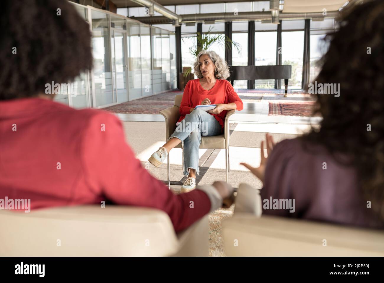 Donna d'affari senior che condivide idee con i colleghi in ufficio Foto Stock