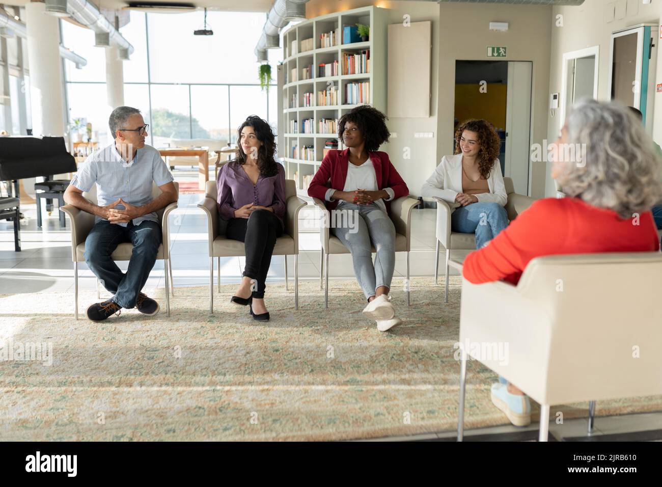 Donne d'affari che guardano un uomo d'affari maturo che condivide idee in ufficio Foto Stock