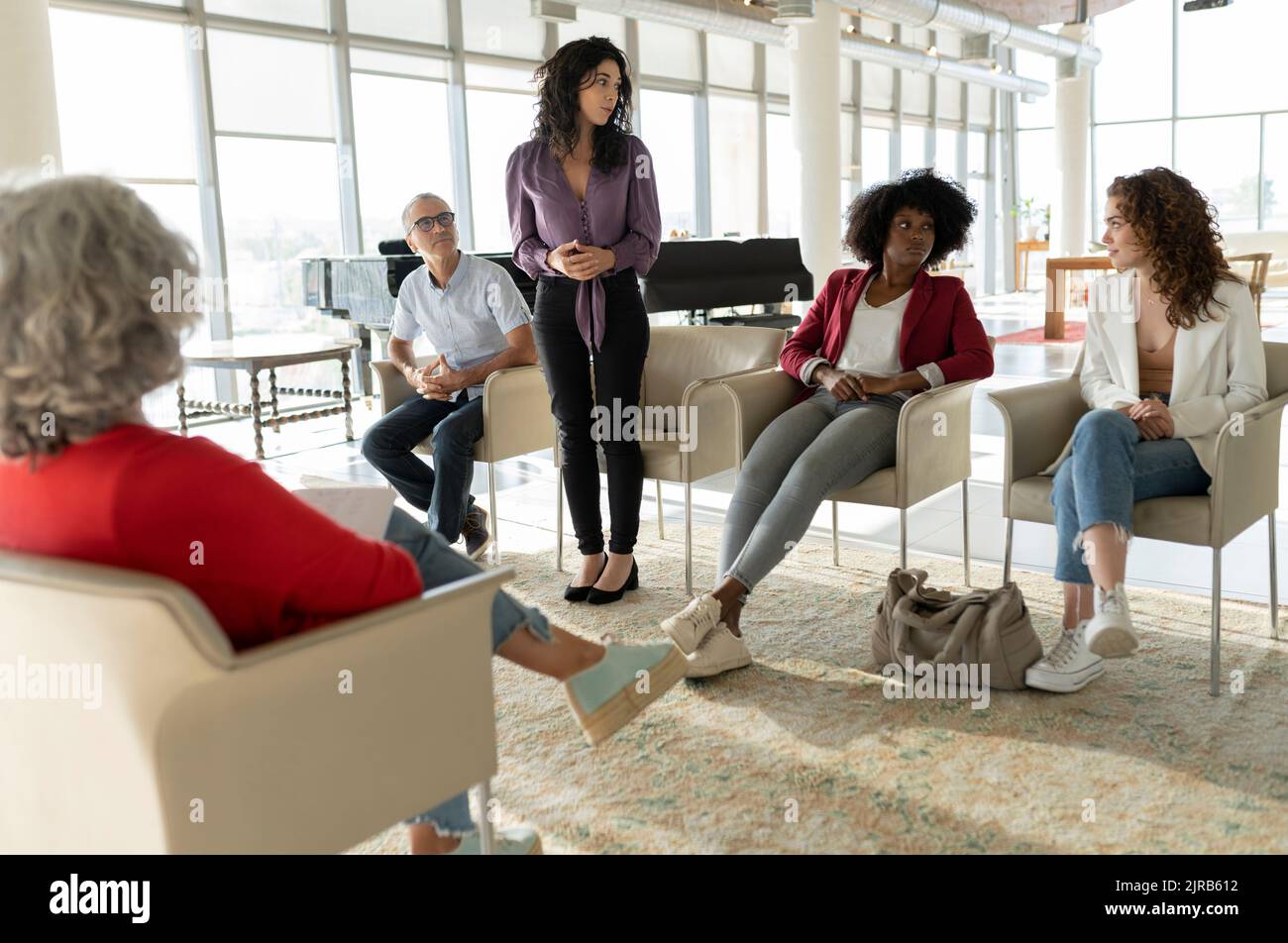 Donna d'affari che condivide idee con i colleghi seduti in ufficio Foto Stock