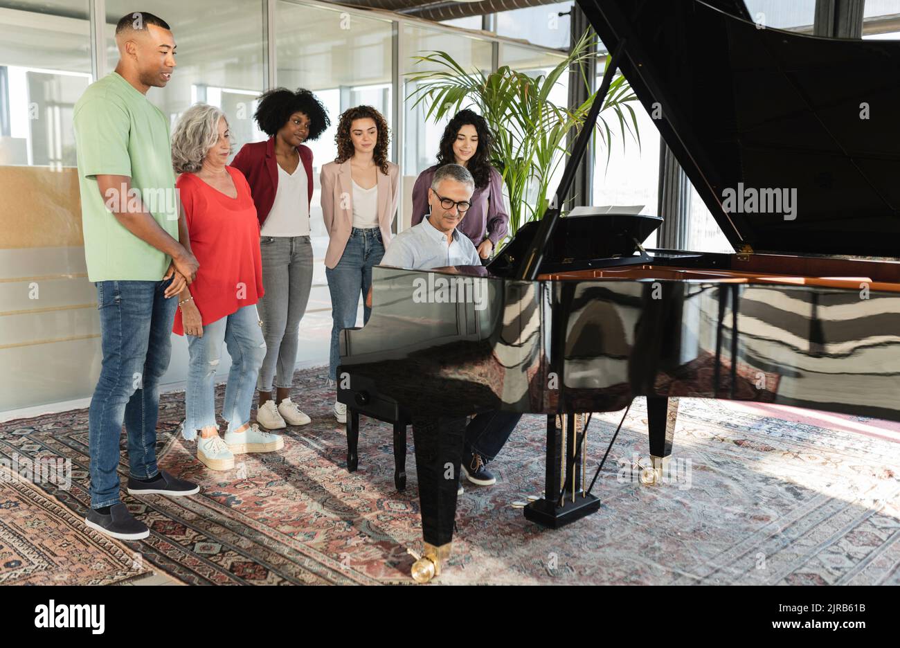 Uomini d'affari e uomini d'affari che guardano un collega che suona il pianoforte Foto Stock