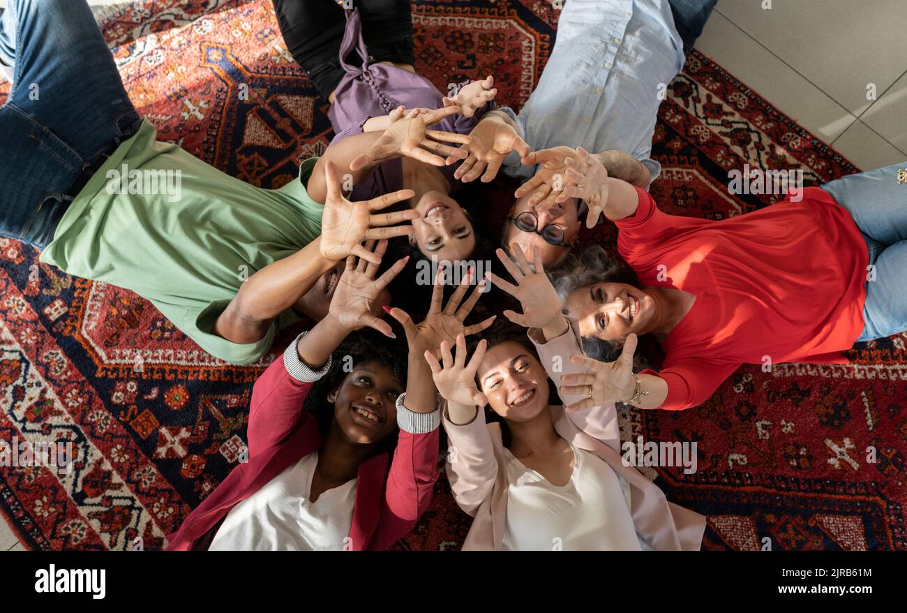 Uomini d'affari felici e donne d'affari gesturing le mani che giacciono insieme sul tappeto Foto Stock