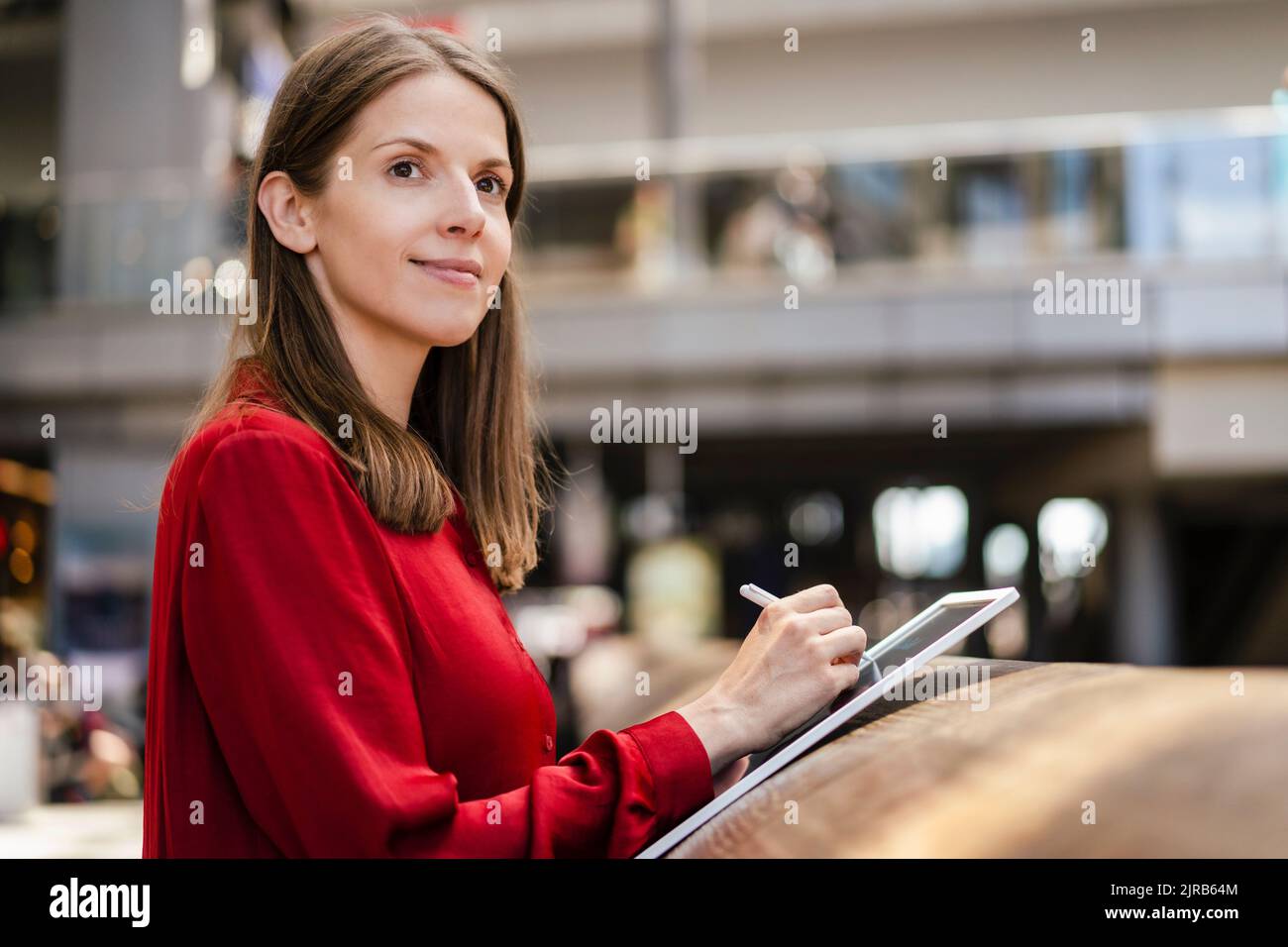 Donna d'affari pensata con penna digitalizzata e tablet PC sul posto di lavoro Foto Stock