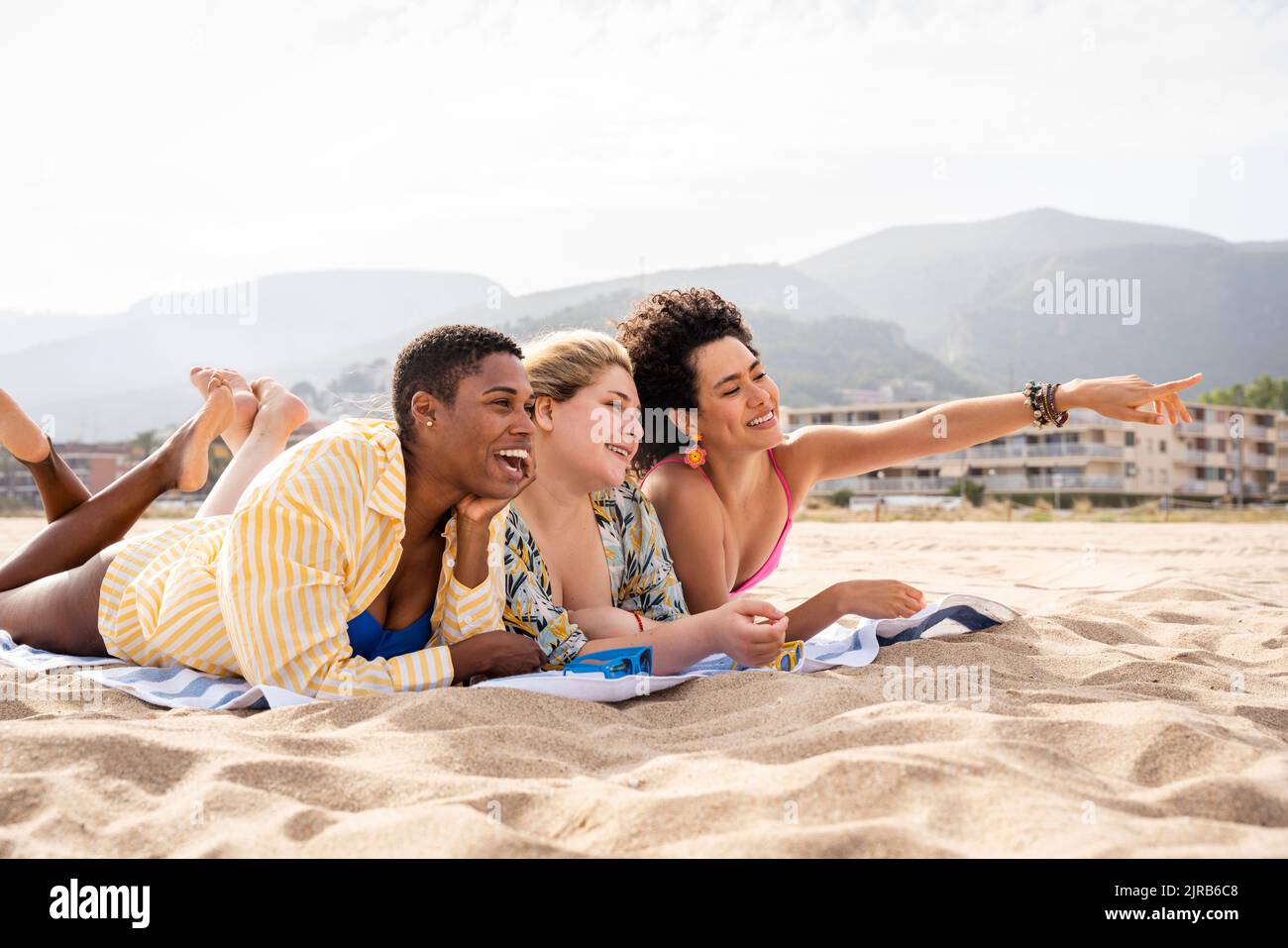 Donna che indica sdraiato con gli amici in spiaggia Foto Stock