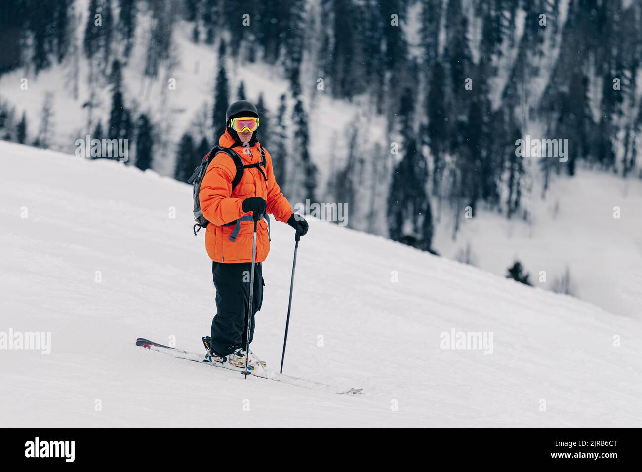 L'uomo sciatore che indossa gli occhiali e casco con segnale di rischio  biologico rendendo selfie mentre è seduto in un impianto di risalita cabina  in corrispondenza di inverno mountain resort Foto stock 