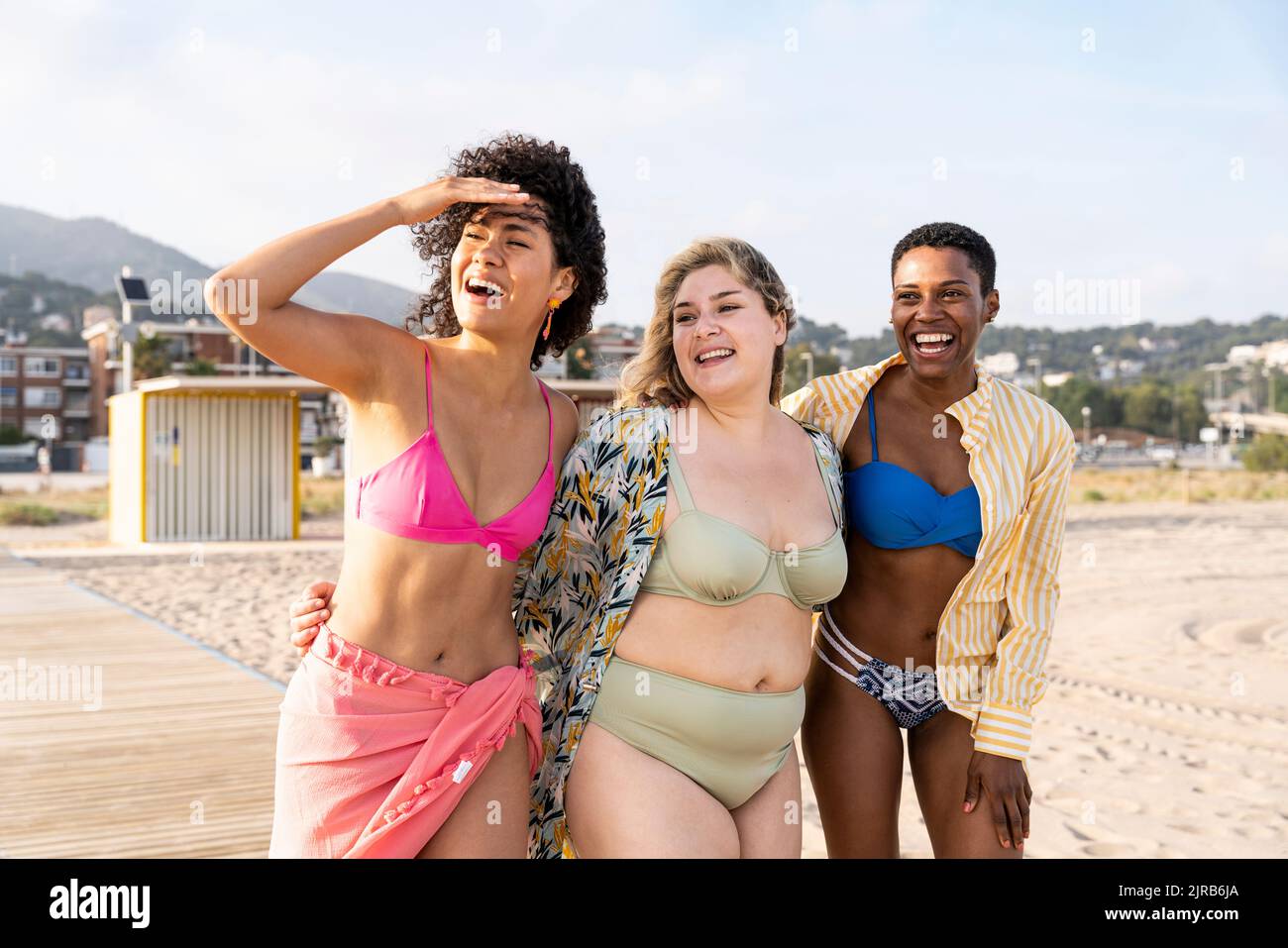 Donna che scherma gli occhi camminando con gli amici in spiaggia Foto Stock