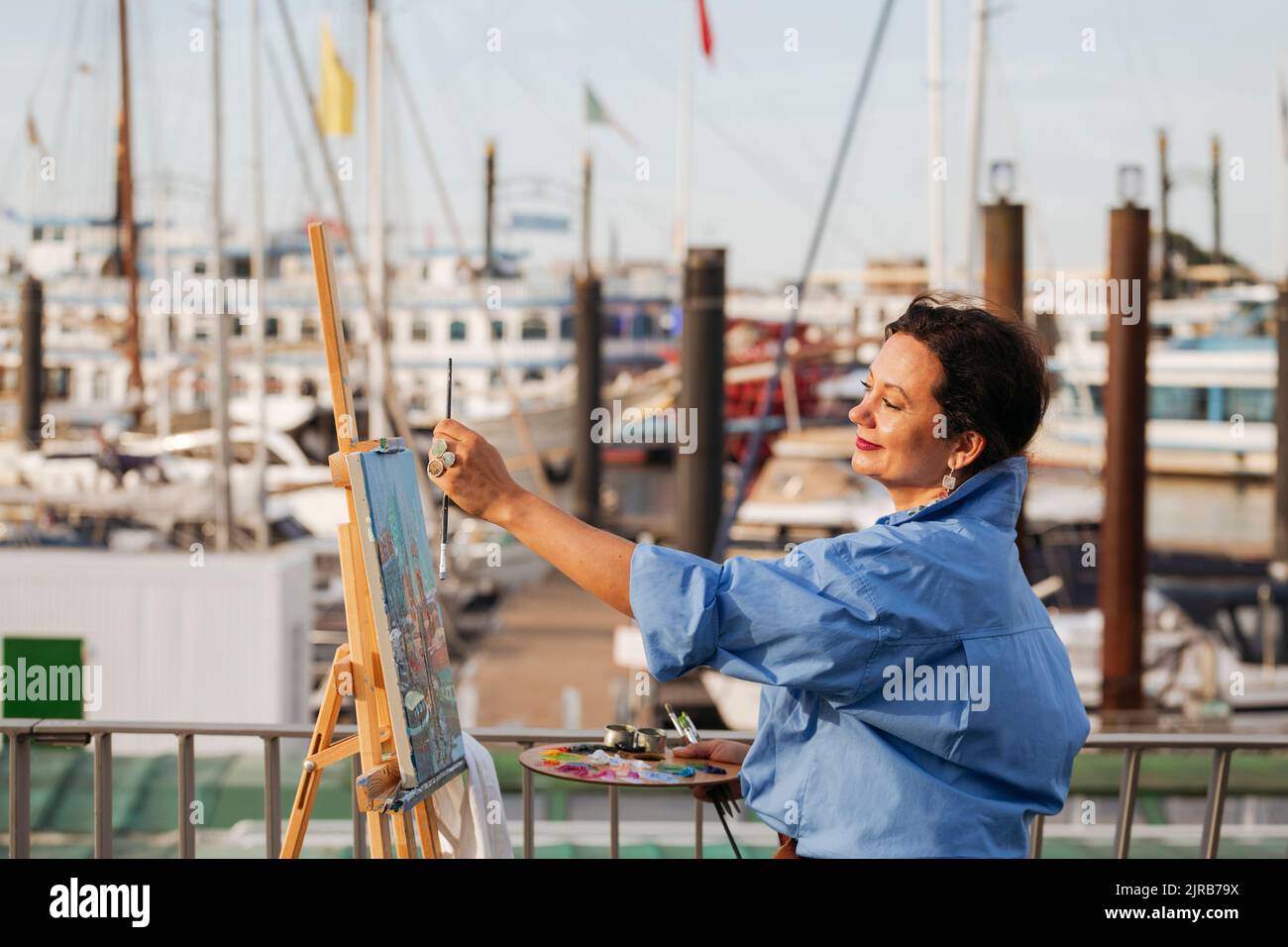 Pittore femmina che misura con cavalletto al porto Foto Stock