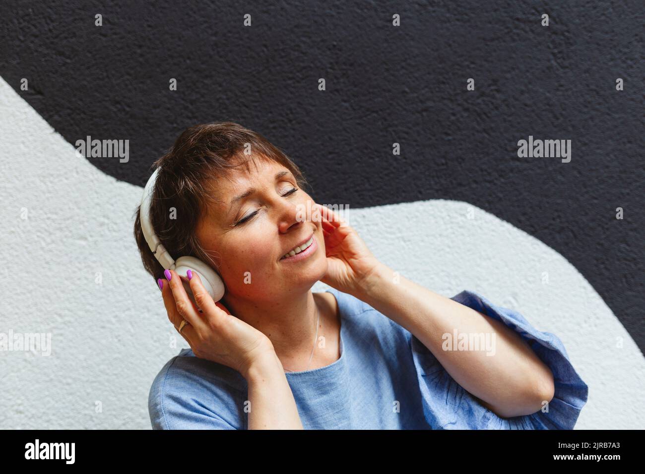 Donna rilassata con occhi chiusi che ascolta la musica con le cuffie Foto Stock