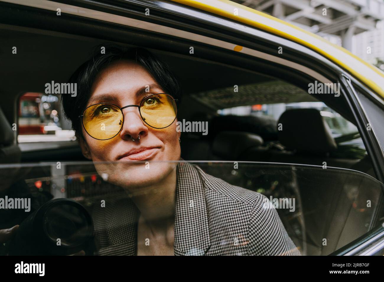 Contemplare una donna d'affari che indossa occhiali da sole gialli seduti in auto Foto Stock