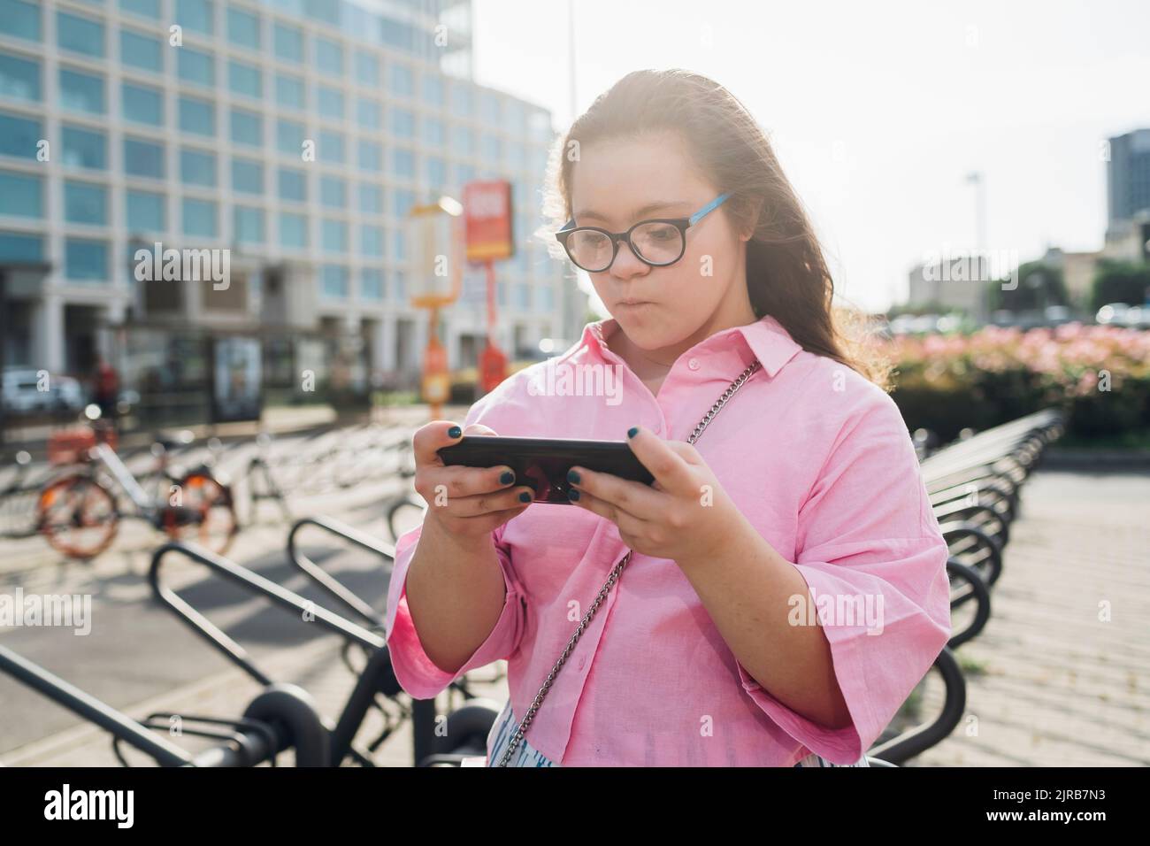 Ragazza adolescente con sindrome di Down che gioca il video gioco su smartphone Foto Stock