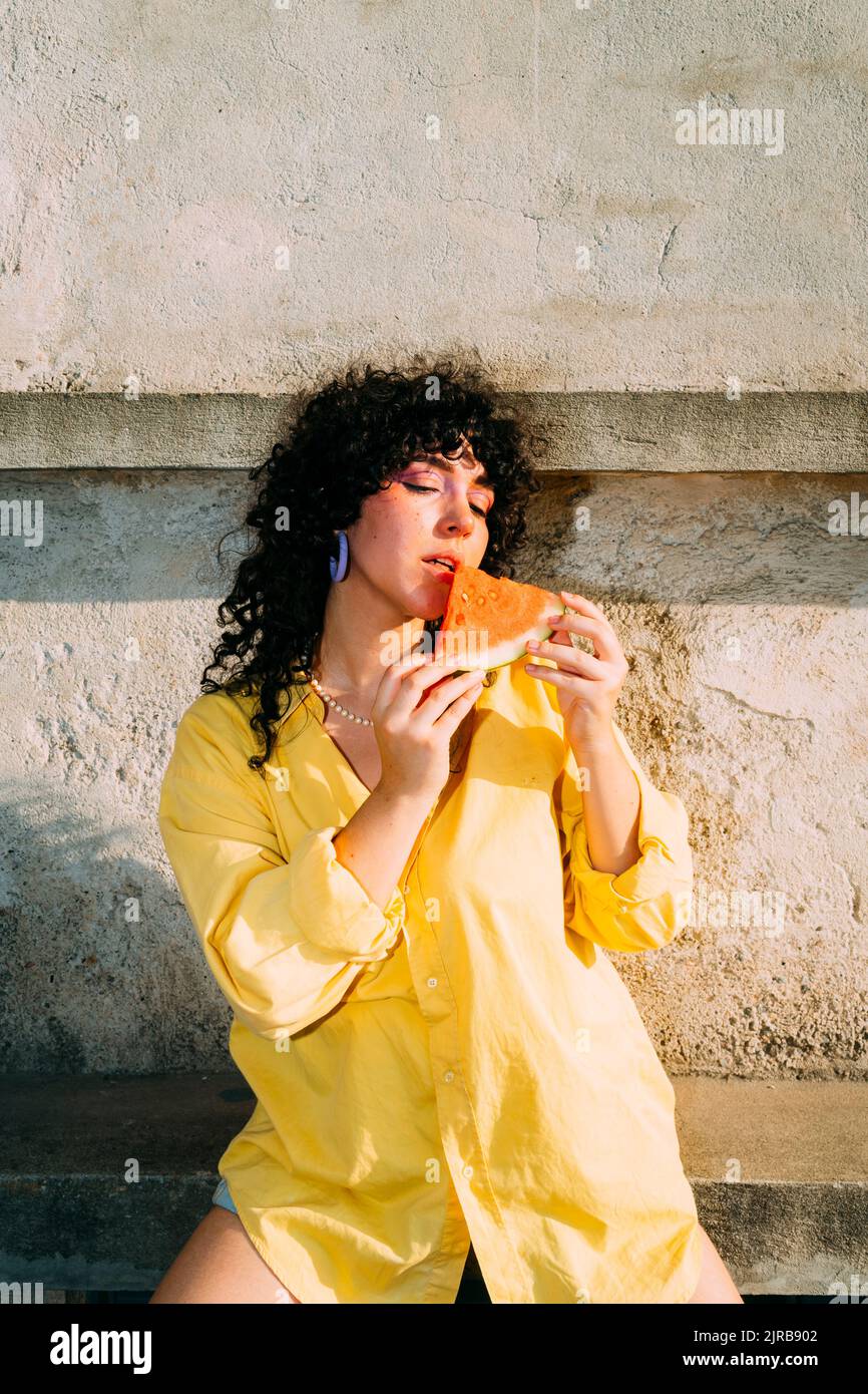 Donna che mangia la fetta di anguria appoggiata sulla panca Foto Stock