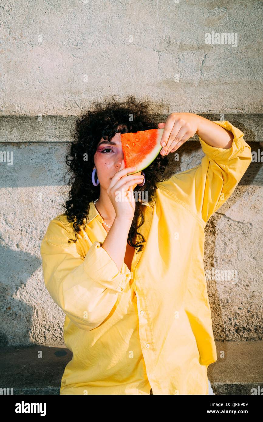 Donna che copre l'occhio con una fetta di anguria fresca Foto Stock
