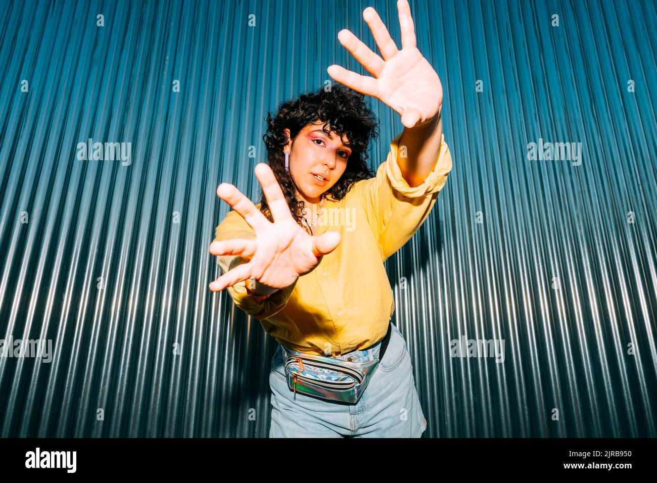 Donna di fiducia che fa il gesto di arresto davanti al muro corrugato Foto Stock