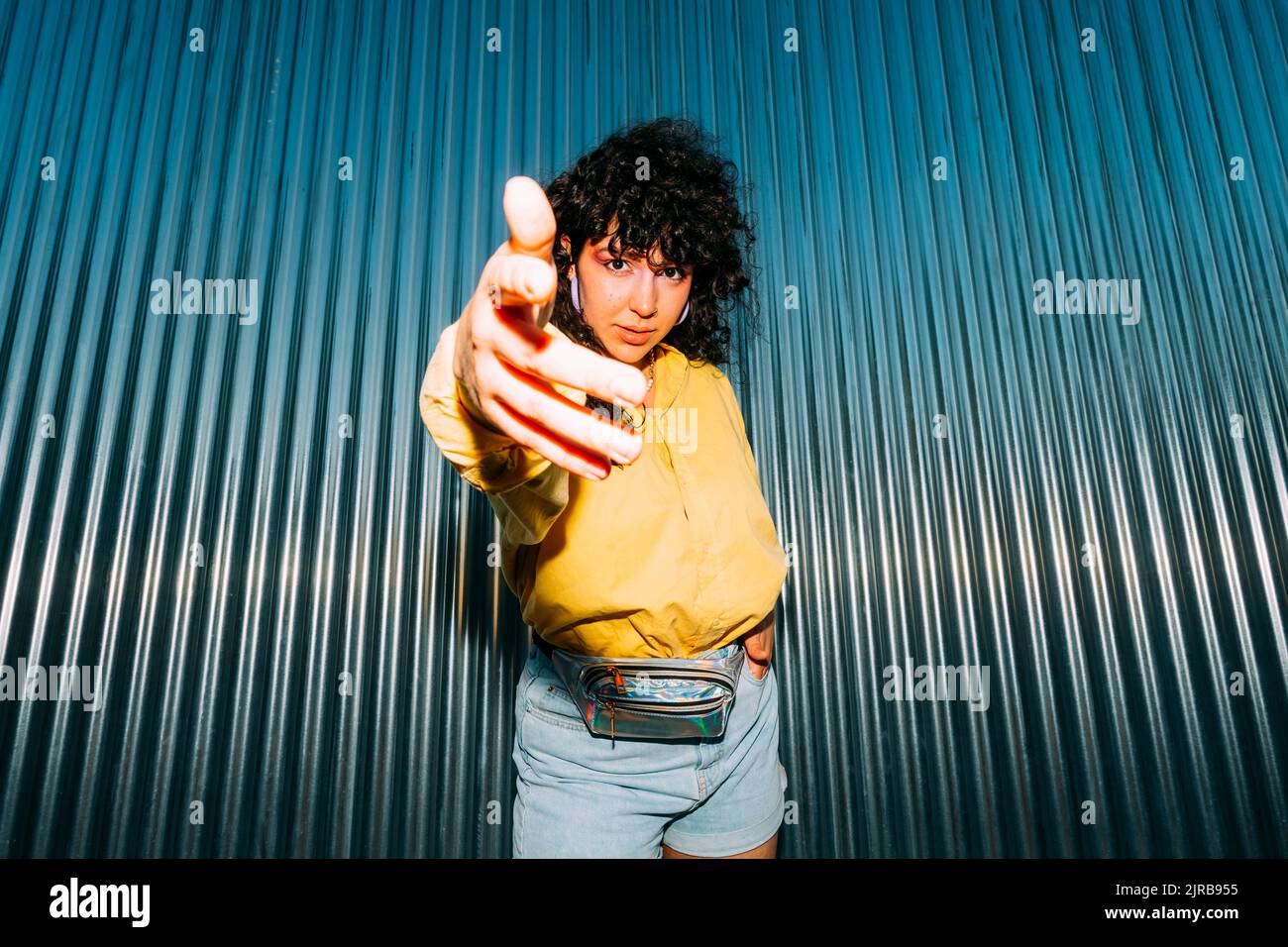 Donna di fiducia gesturing davanti al muro corrugato Foto Stock