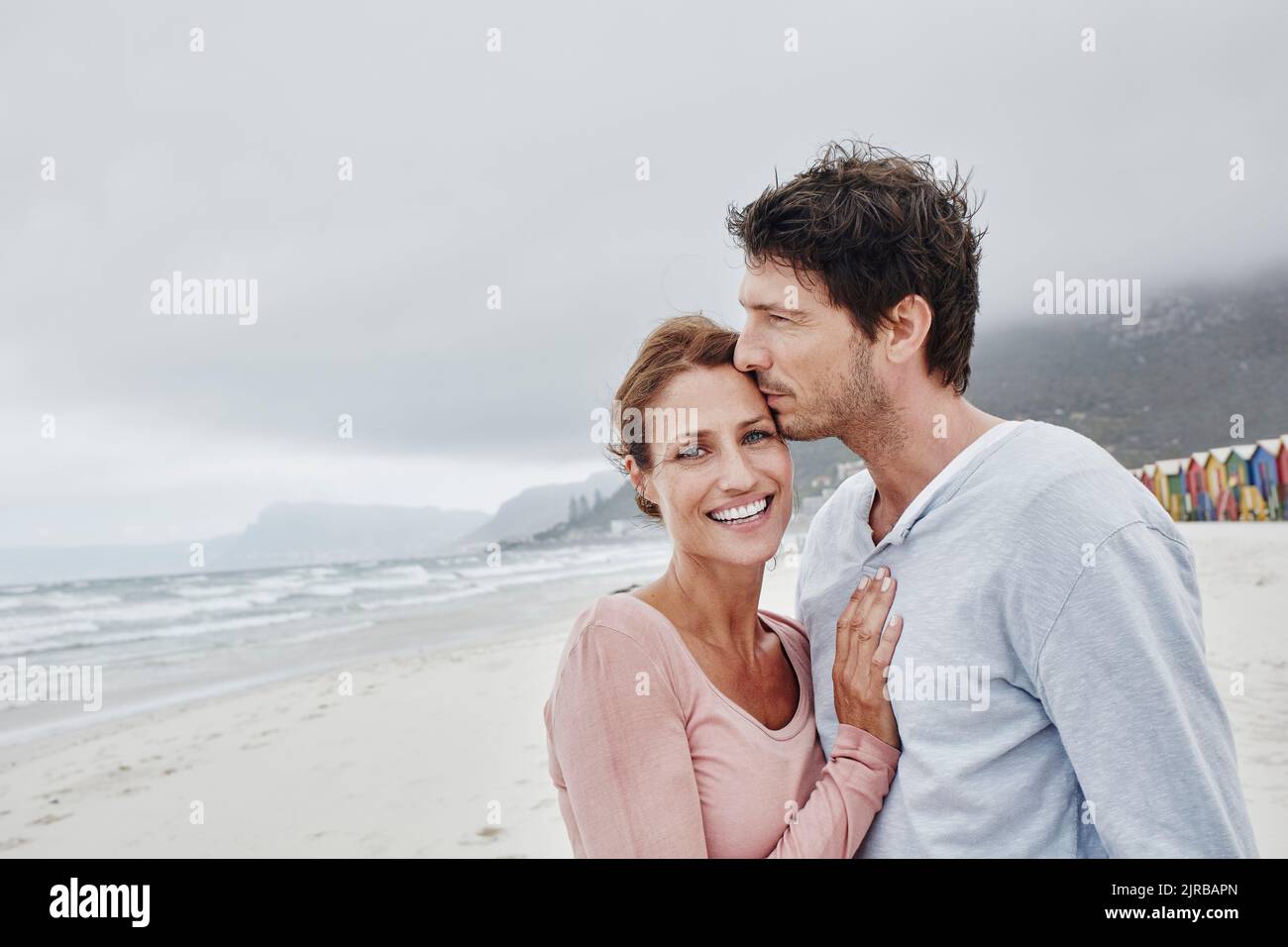 Affecionate uomo baciare donna sulla fronte in piedi al mare Foto Stock