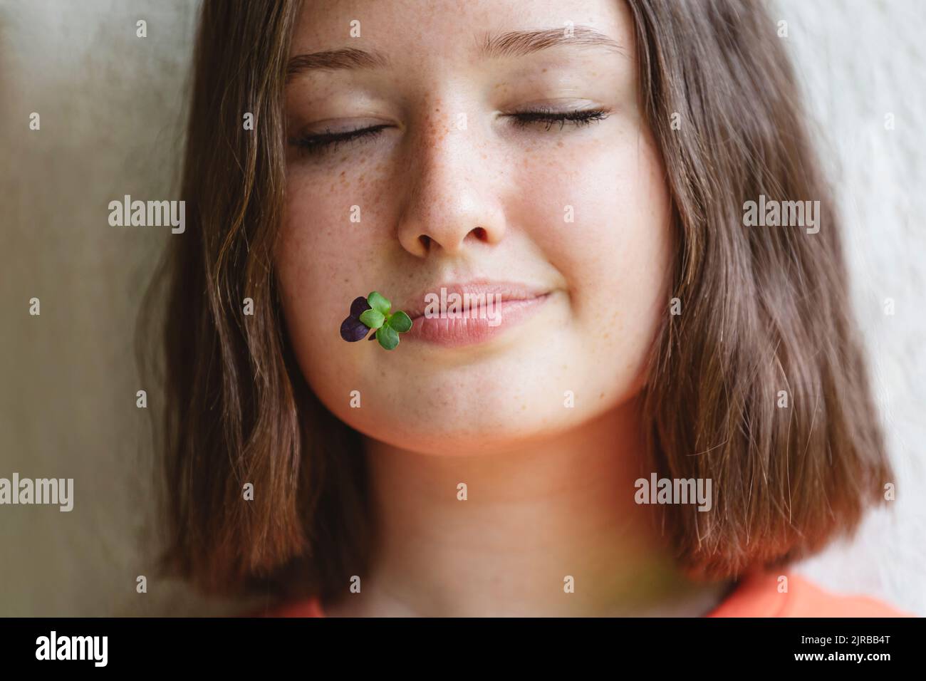 Ragazza adolescente con gli occhi chiusi e microgreens tra le labbra Foto Stock