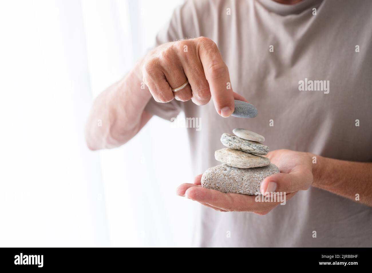 Uomo impilando pietre a portata di mano a casa Foto Stock