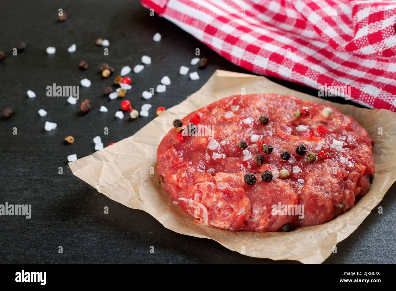 Hamburger di bistecca di manzo appena sminuzzato e crudo con spezie, su un tavolo di ardesia nera, spazio copia, vista dall'alto Foto Stock