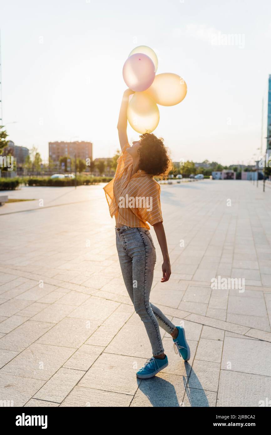 Giovane donna con palloncini rialzati a mano Foto Stock