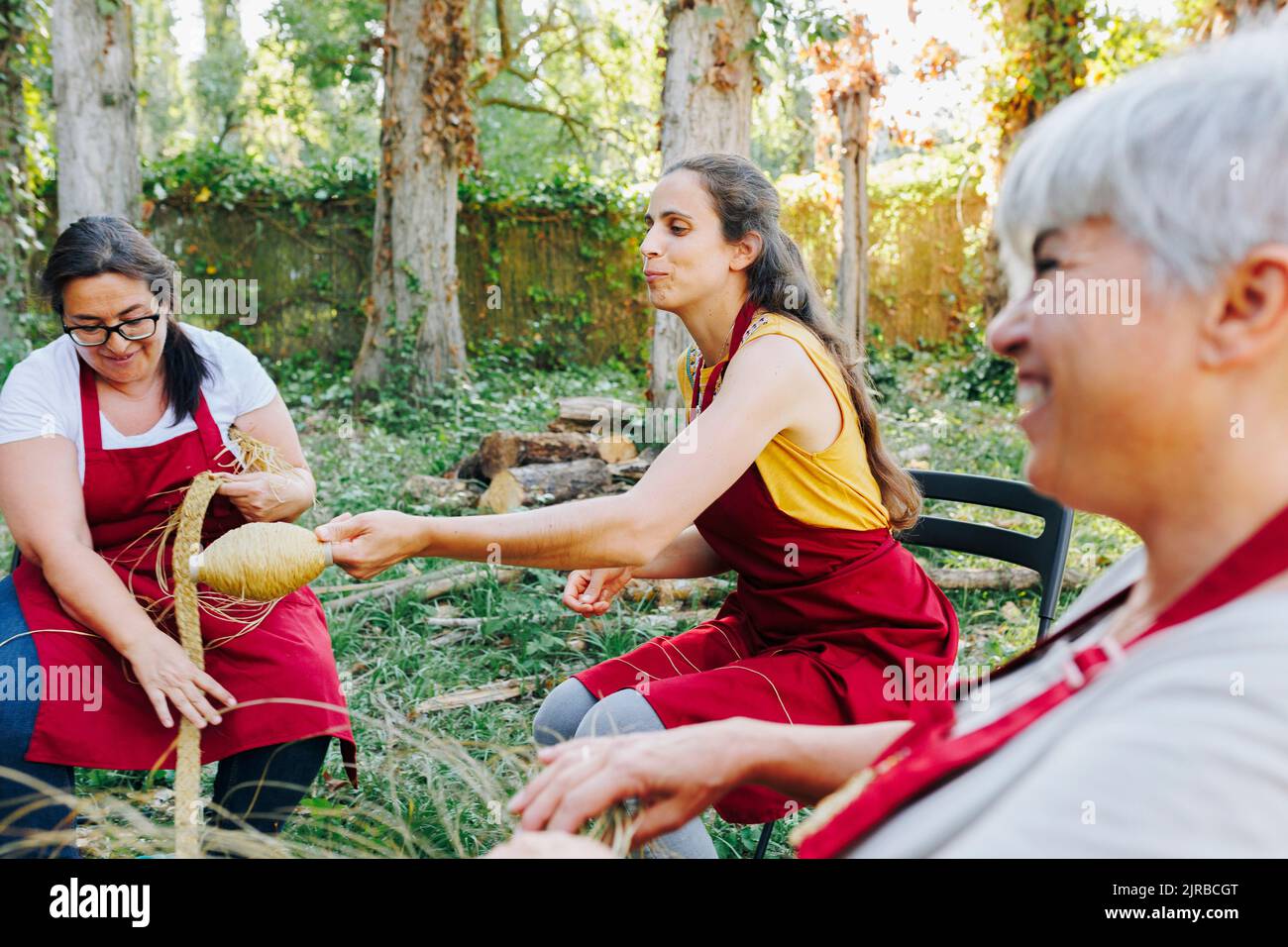 Tessitura artigianale sorridente con erba esparte in giardino Foto Stock