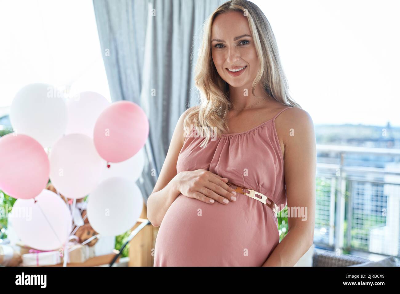 Donna incinta sorridente vestito rosa all'acquazzone del bambino Foto Stock