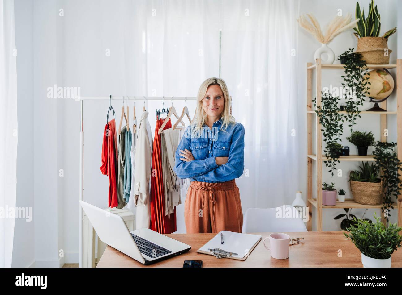 Designer di moda sicuro in piedi con le braccia incrociate in casa ufficio Foto Stock