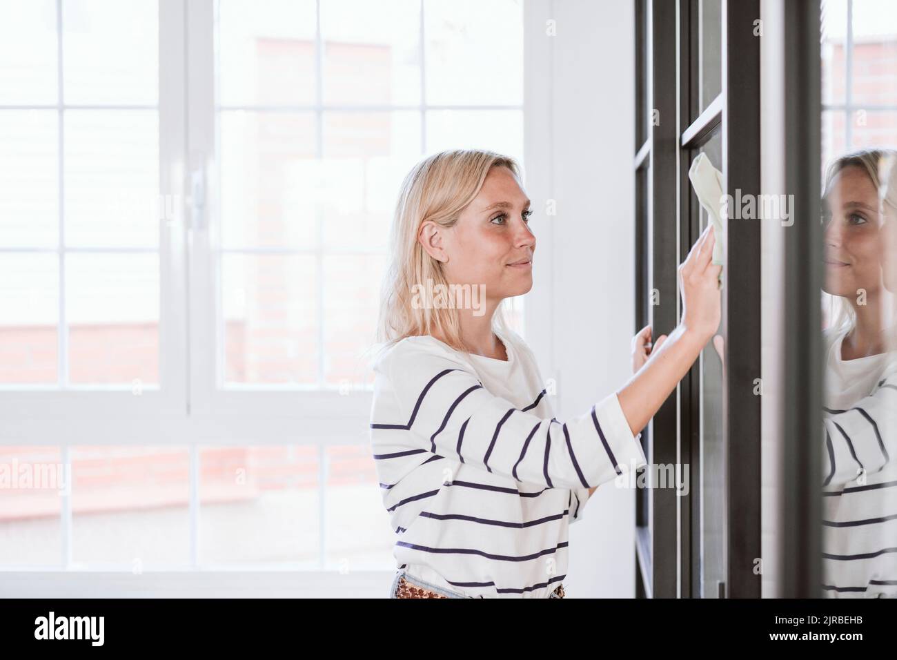 Donna che pulisce la porta con la polvere a casa Foto Stock