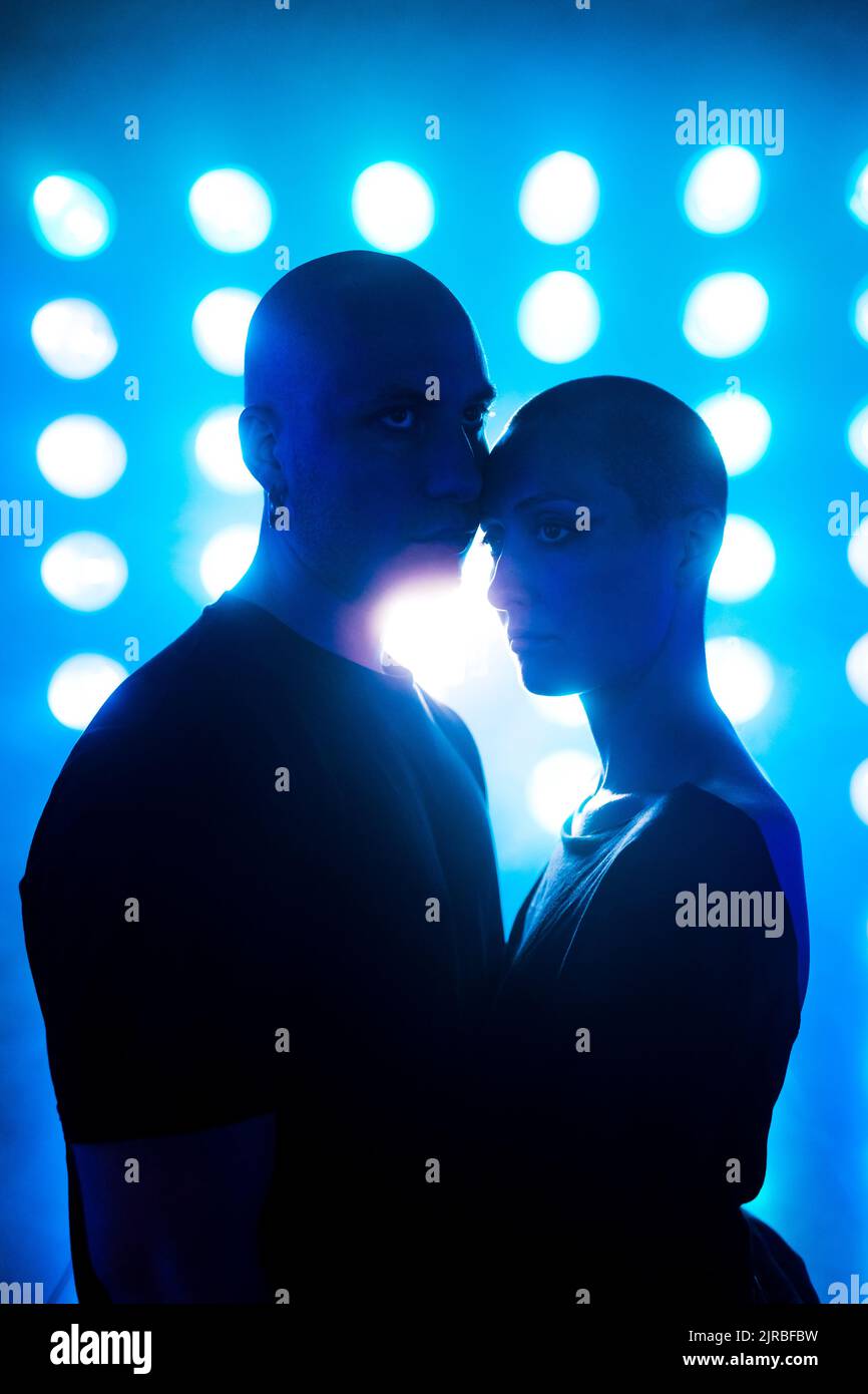 Coppia di hipster in piedi di fronte alle luci incandescenti Foto Stock