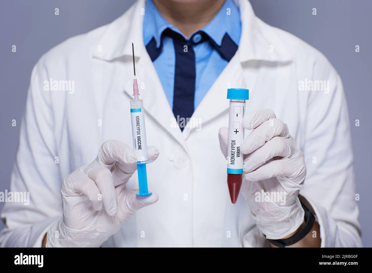 Primo piano su moderna medico femminile in vestito medico bianco con siringa di vaccino monkeypox e provetta monkeypox isolato su sfondo grigio. Foto Stock
