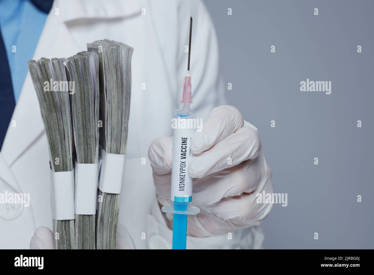 Primo piano su medico femminile moderno in vestito medico bianco con siringa di vaccino di scimmietta e confezione di denaro su sfondo grigio. Foto Stock