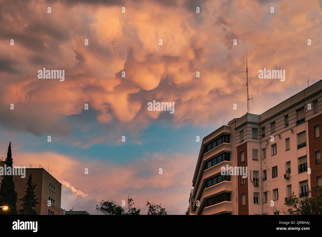 Spagna, Madrid, tempesta nuvole che si radunano sugli edifici della città al tramonto Foto Stock