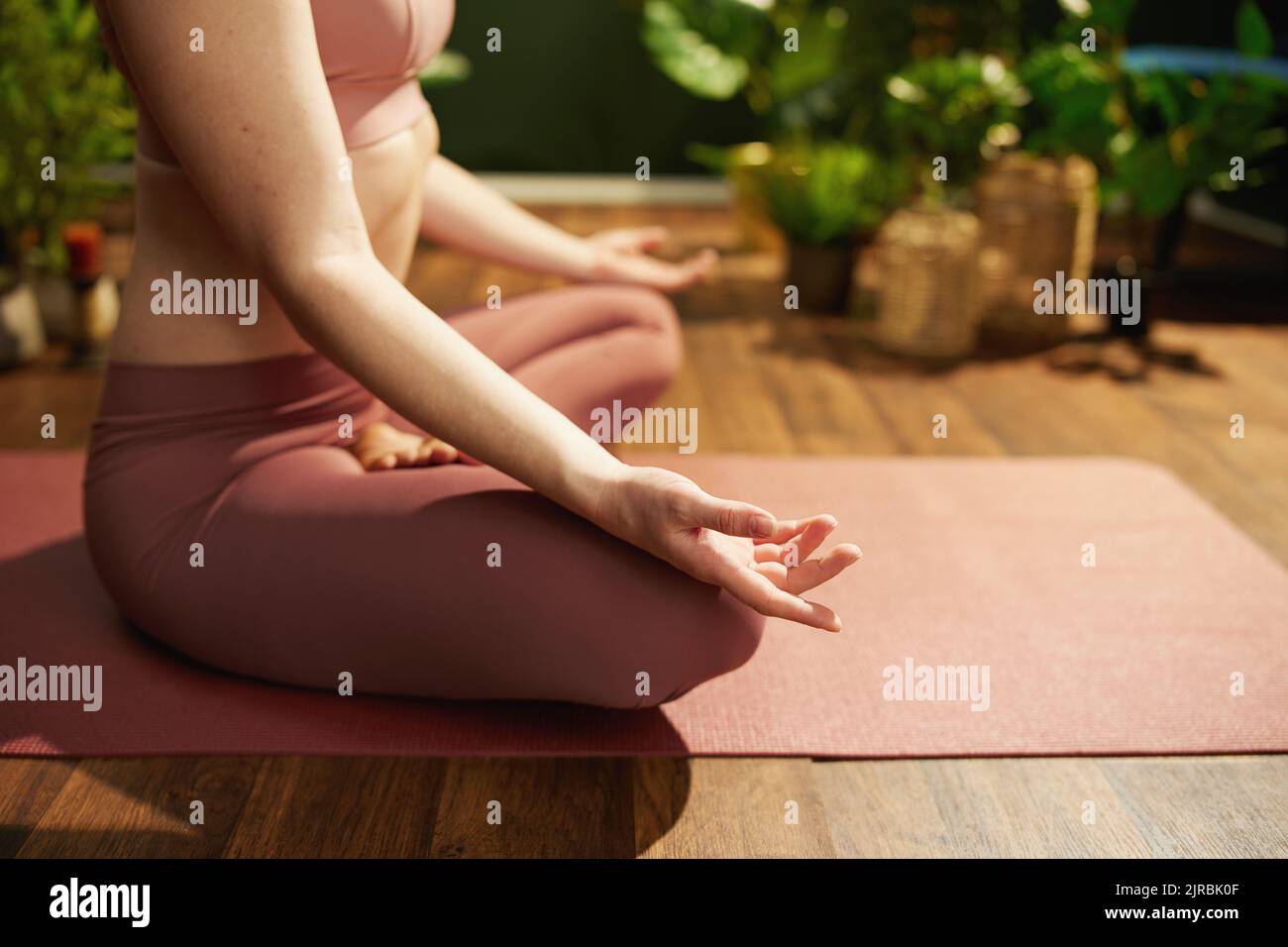 Primo piano sulla donna nella casa verde che fa yoga. Foto Stock