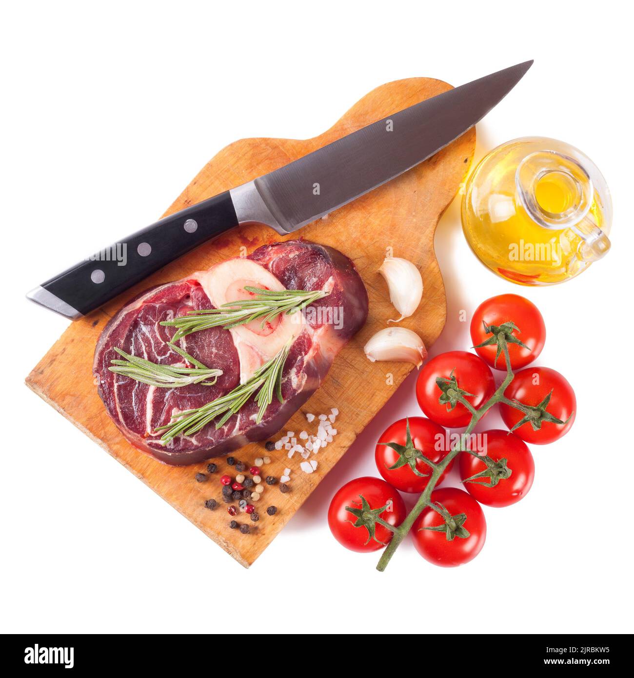 bistecca di manzo crudo con osso e coltello, spezie, rosmarino e ingredienti da cucina su tagliere di legno isolato su sfondo bianco. Foto Stock