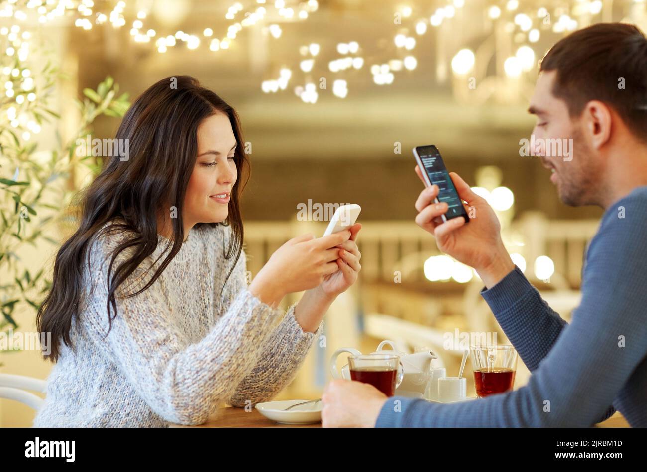 Coppia felice con gli smartphone bere il tè al caffè Foto Stock