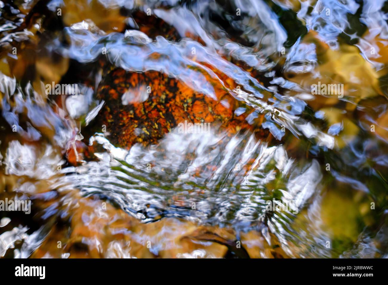 Rocce colorate, acque fluenti e riflessi del sole in un torrente in primo piano Foto Stock
