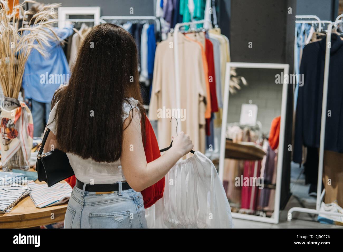 Seconda mano. Moda sostenibile. Giovane donna Latina che acquista abiti sostenibili usati da un negozio di beneficenza di seconda mano Foto Stock