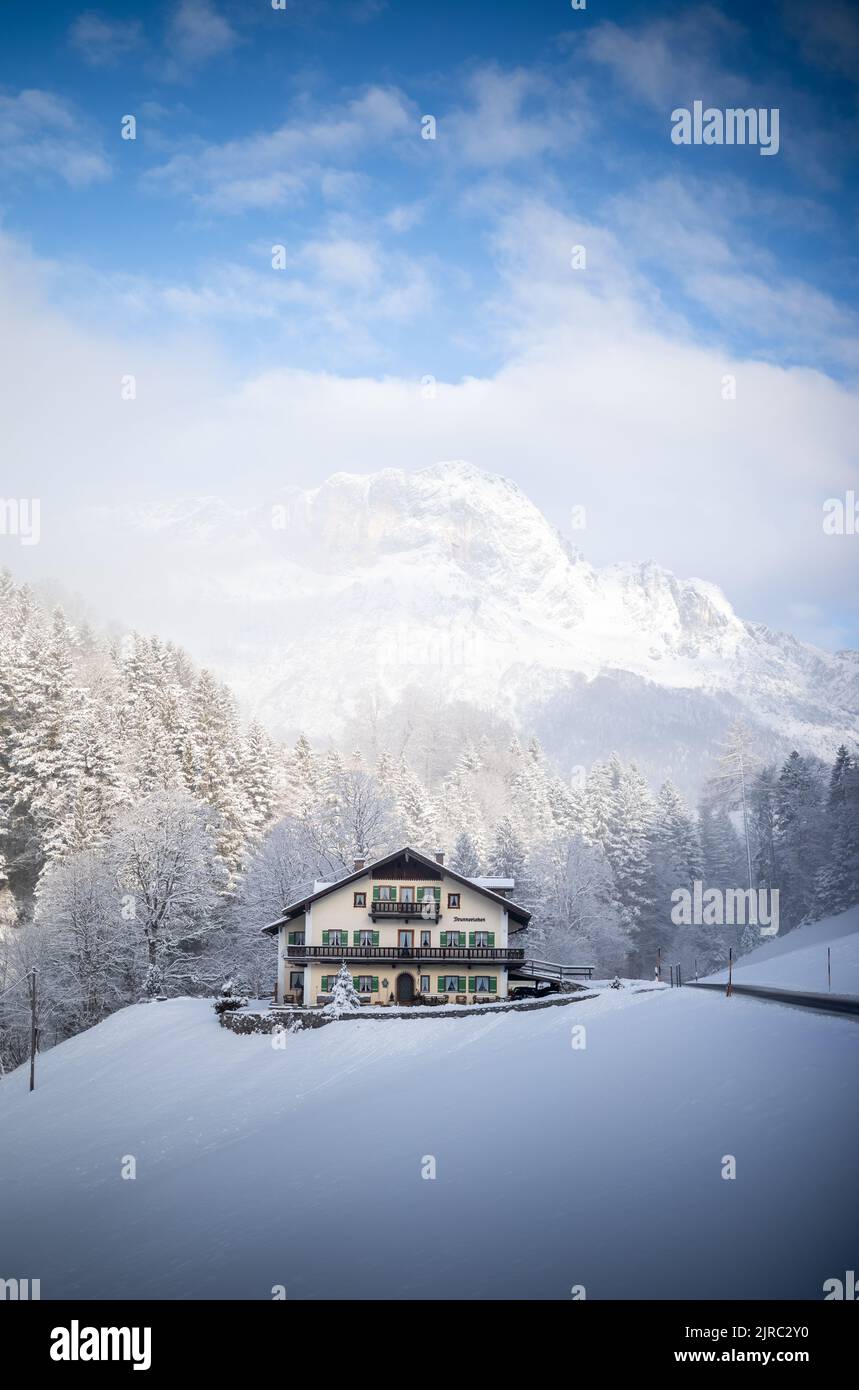 Haus in verschneiter Winterlandschaft mit Bergkulisse. Foto Stock