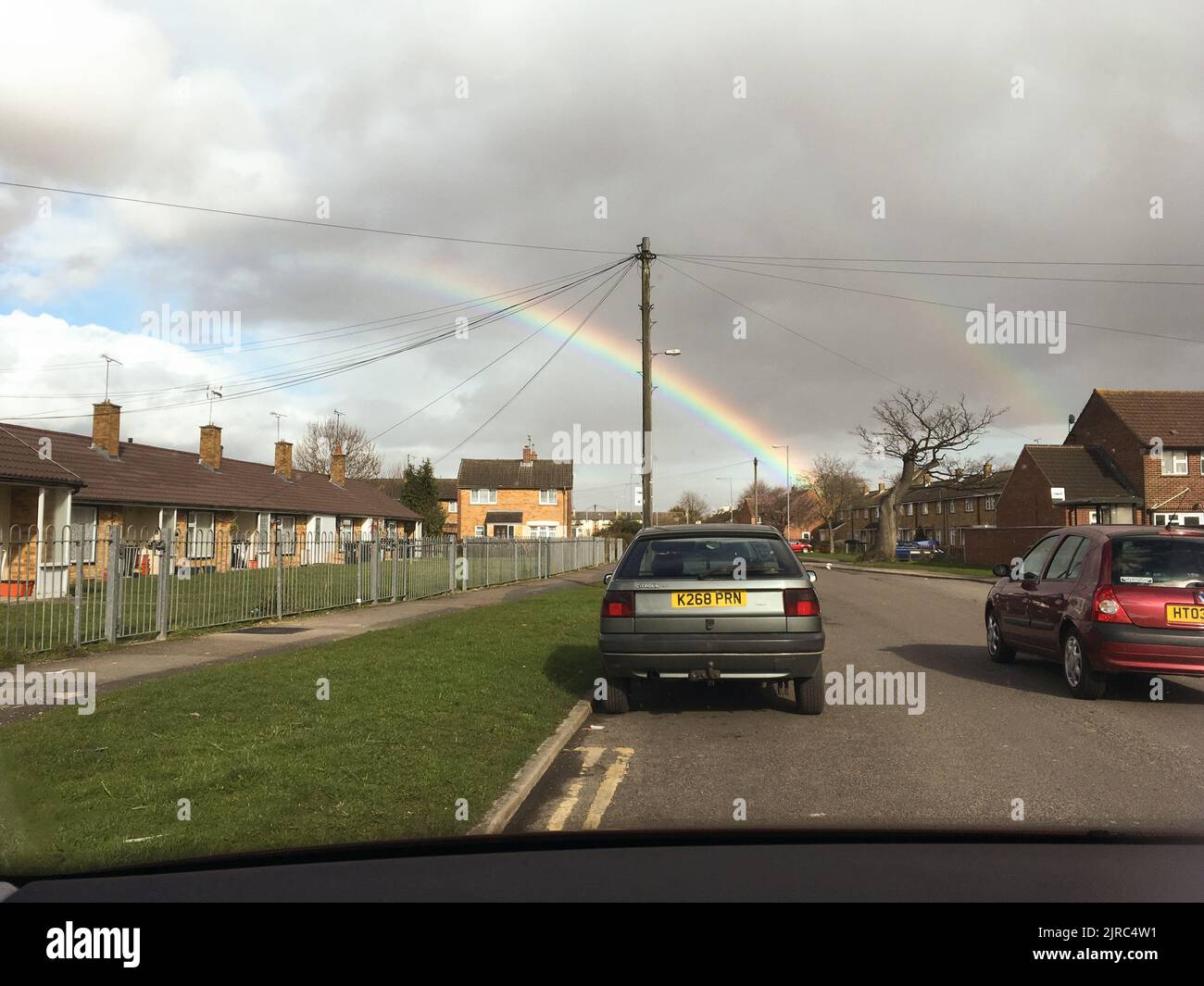 Una vista di auto su una strada e doppio arcobaleno in pioggia pomeridiana Foto Stock