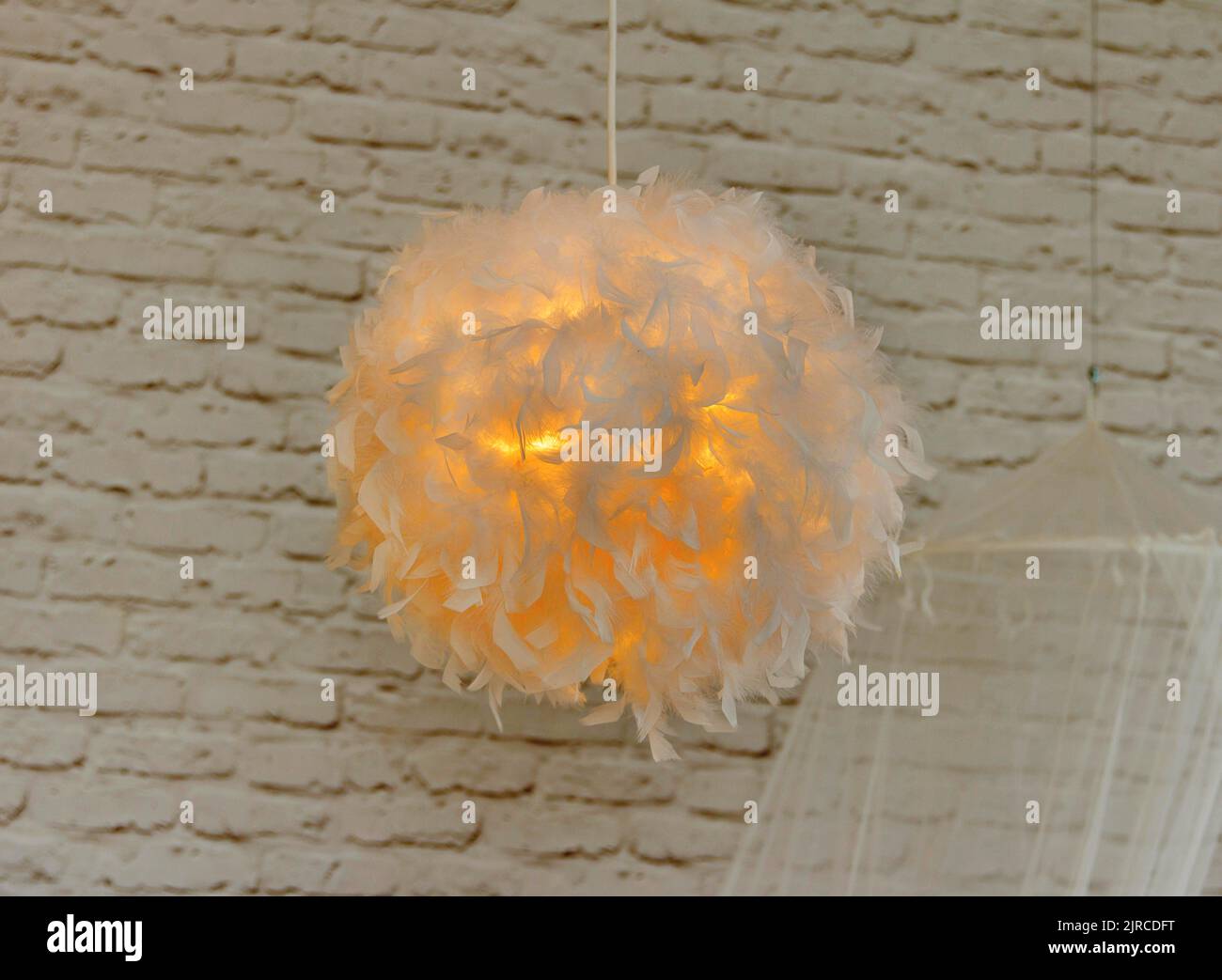 Moderna lampada con abajur di piume bianche, dà luce romantica in camera da letto Foto Stock