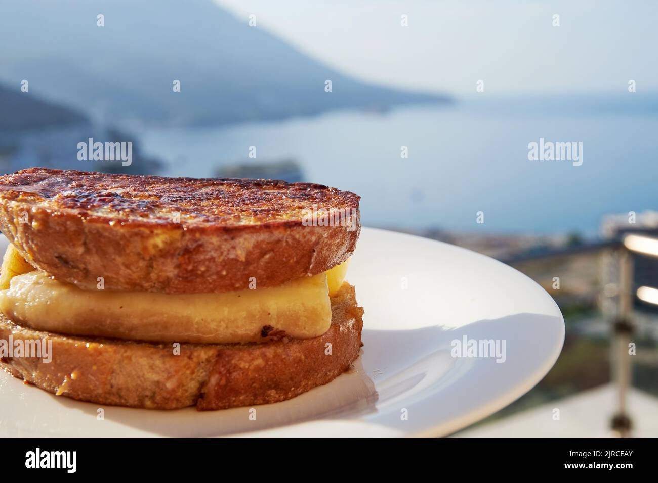 Toast alla francese con banana e cannella sulla terrazza di un hotel sul mare. Vacanze estive e viaggi Foto Stock