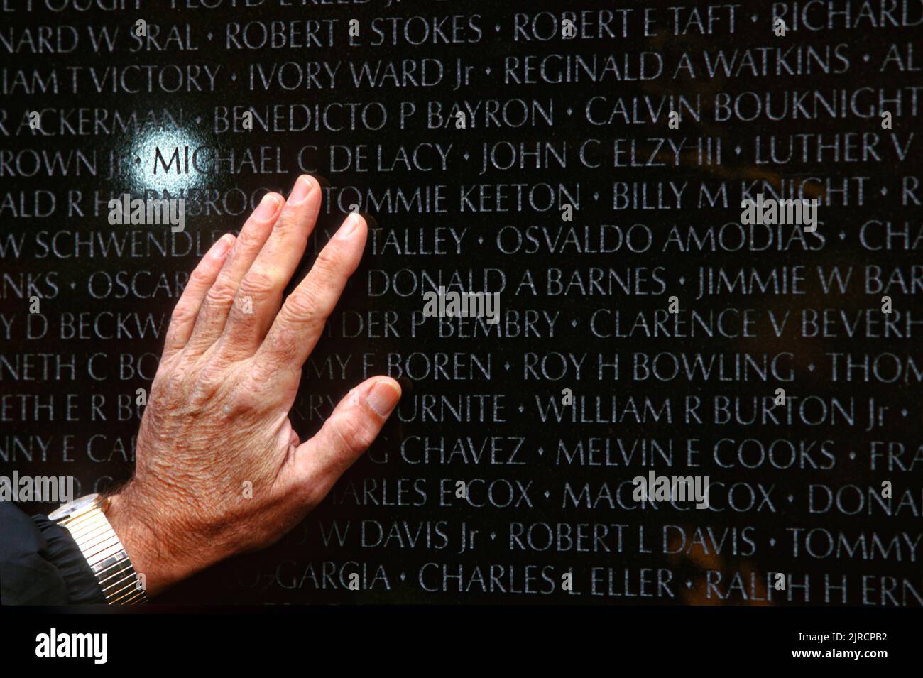 Un parente di un soldato ucciso nella guerra del Vietnam si allunga per toccare il nome inciso nel Vietnam Veterans Memorial a Washington, DC. Foto Stock