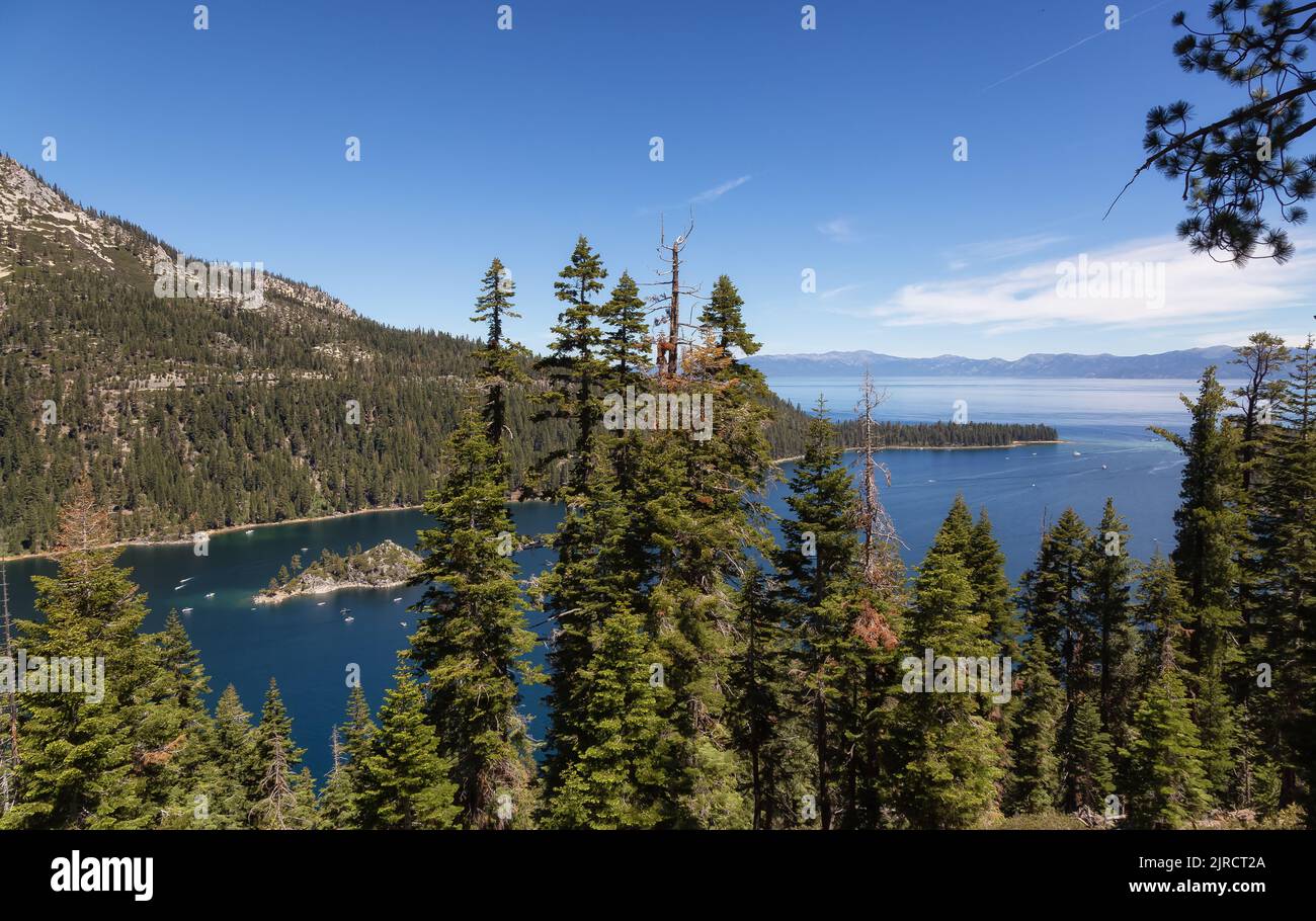 Vista di grande baia e lago con barche, piccola isola, alberi e montagne. Foto Stock
