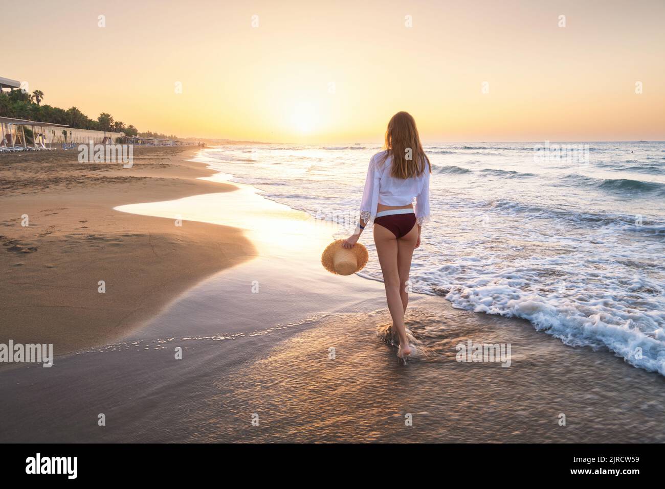 Bella giovane donna con cappello di paglia sul mare con le onde Foto Stock