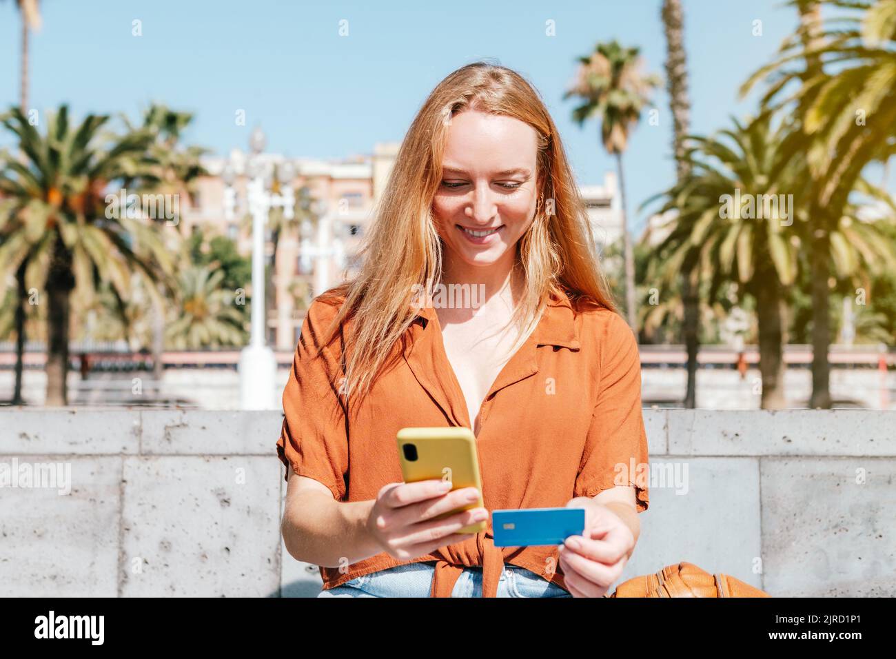 donna turistica caucasica utilizzando il telefono e la carta di credito per fare shopping online Foto Stock