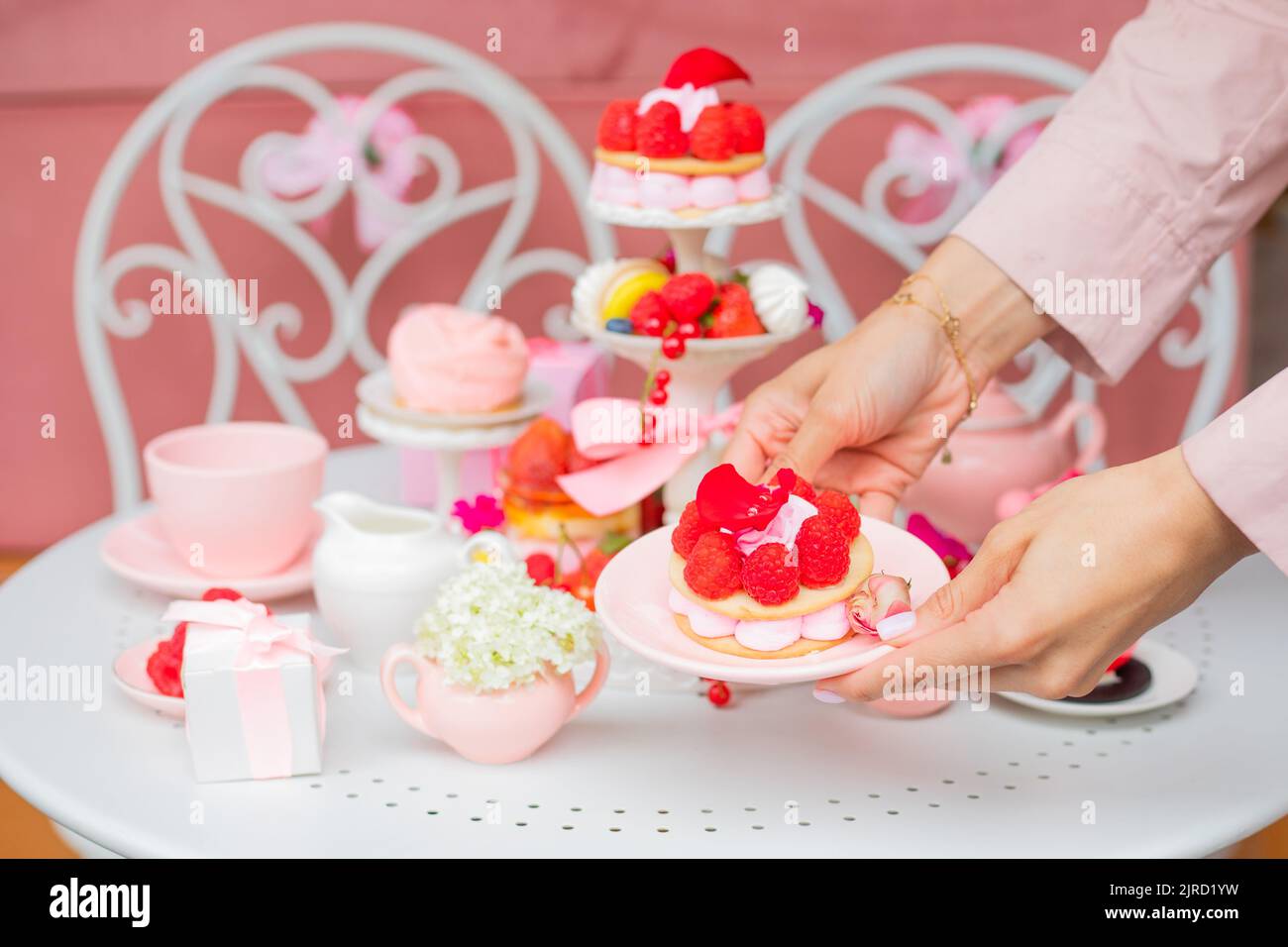 Mani di donna corto mettendo piatto puncake di bacche rosa sul tavolo nel ristorante, caffè. Dessert tavolo compleanno evento festivo Foto Stock