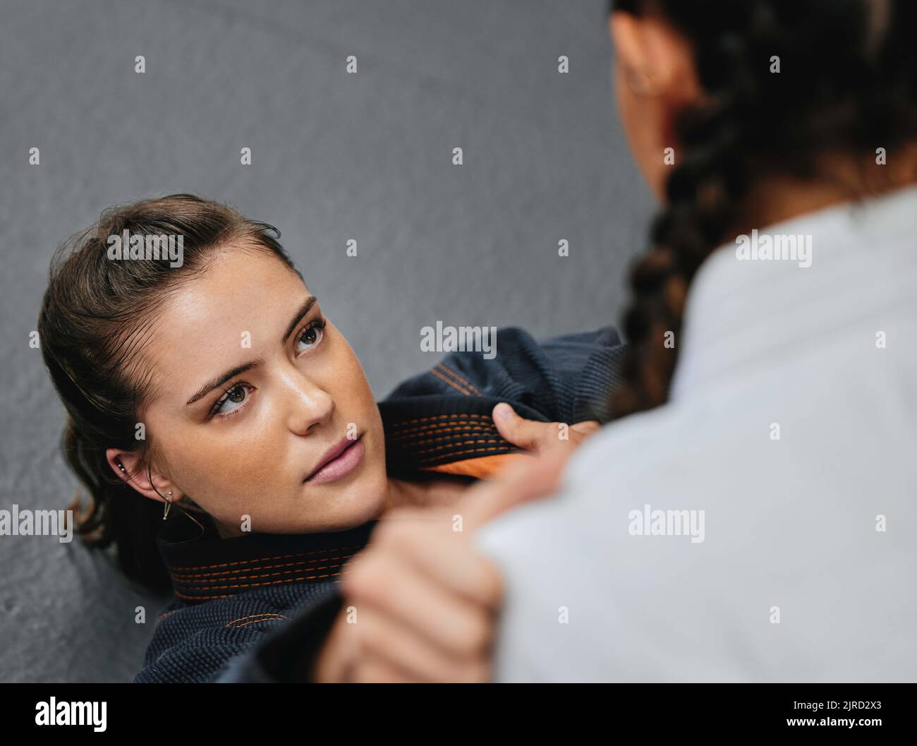 Le giovani donne praticano e allenano il karate o il judo in una palestra dojo per autodifesa. Studenti o combattenti professionisti che si trovano sul pavimento mentre Foto Stock